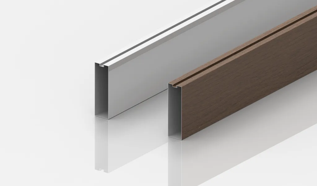 Two rectangular metal profiles are standing upright on a glossy white surface. The profile on the left is silver with a white insert, and the one on the right is brown with a wood-like texture. Both profiles have a slot along the top edge.