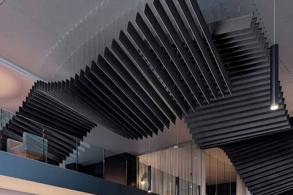 Large, black, rectangular acoustic panels are suspended in a twisting, wave-like pattern from a modern ceiling above a glass-walled mezzanine in a contemporary interior space.