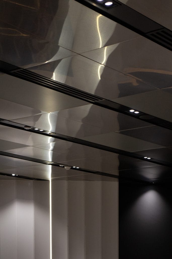 A modern ceiling with metallic reflective panels and built-in recessed lights, casting soft illumination onto the sleek, minimalist walls below.
