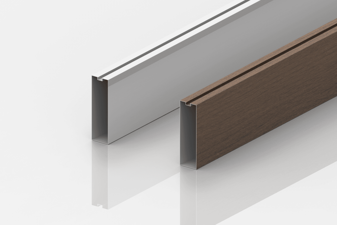 Two rectangular metal profiles are standing upright on a glossy white surface. The profile on the left is silver with a white insert, and the one on the right is brown with a wood-like texture. Both profiles have a slot along the top edge.