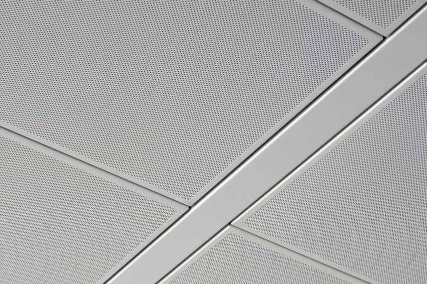 Close-up of a modern suspended ceiling with gray perforated metal panels arranged in a geometric grid pattern, featuring diagonal and horizontal dividing lines.
